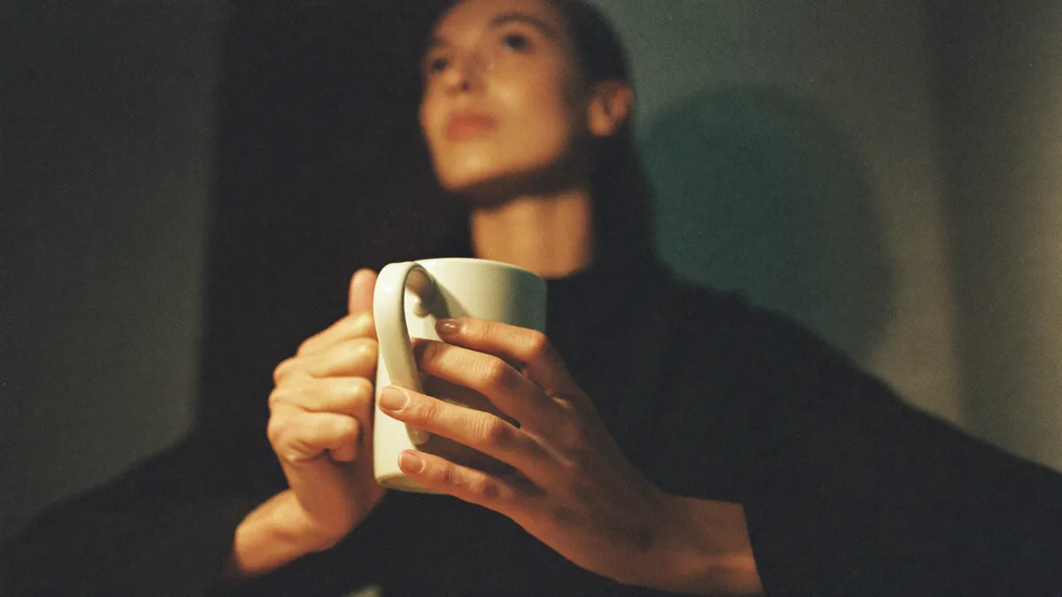 A woman at a tidy desk late at night, composed on the surface, shoulders tight · high functioning anxiety in women