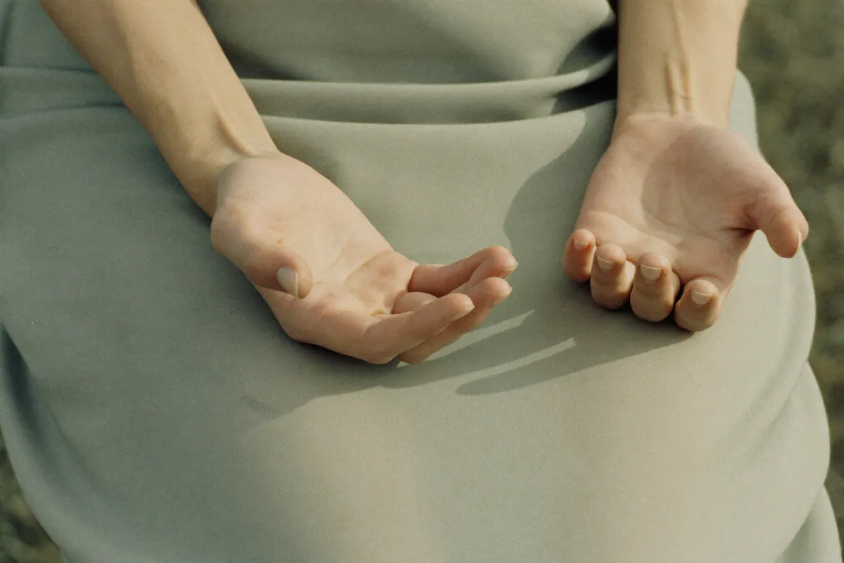 A woman's open, upturned hands resting in her lap, the receiving posture at the heart of learning to receive