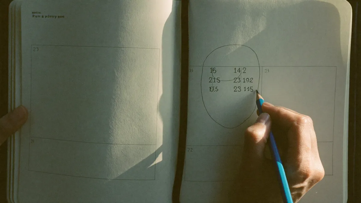 A woman working out her life path number by hand at a sunlit table, a birthday circled on a calendar
