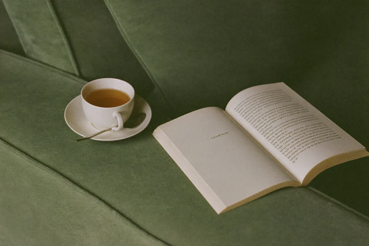 A cup of tea gone cold beside an open book on a sofa, the rest you reach for but cannot settle into