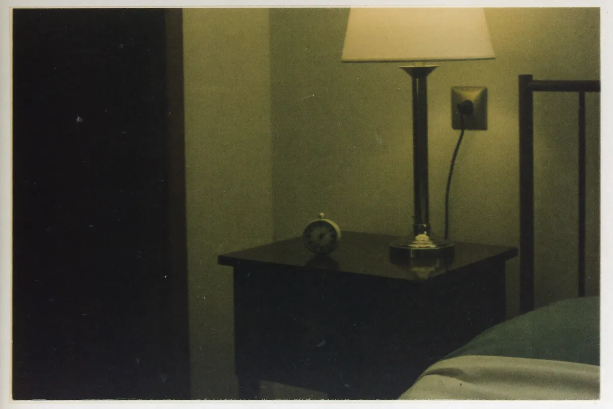 A dim bedside lamp and a small clock in a quiet dark bedroom, the exhausted but wide-awake hours of feeling wired but tired